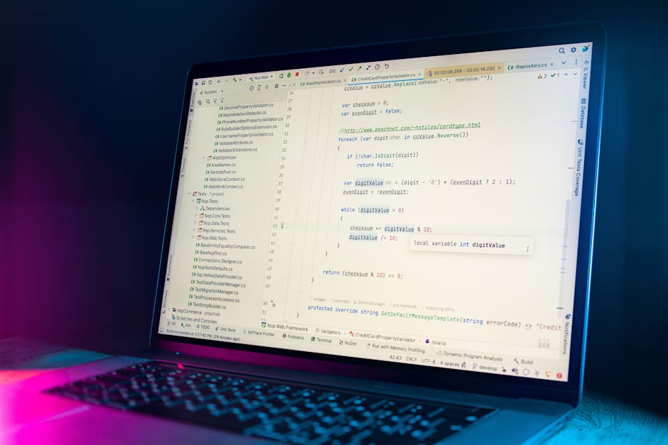 A close-up digital image of a computer screen displaying lines of colorful, blurred computer programming code on a black background. The code consists of various colored syntax elements including red,